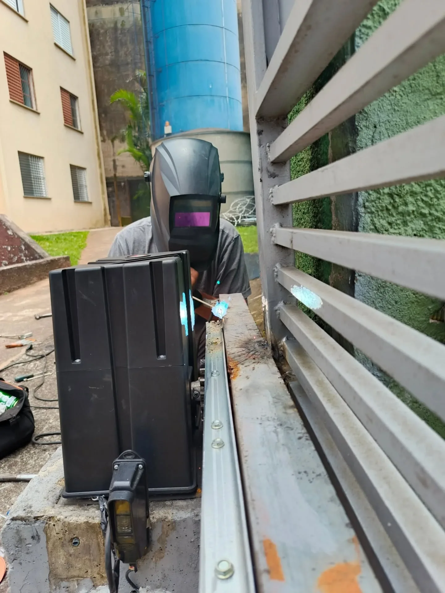 técnico soldando a cremalheira no portão de correr, com o motor deslizante instalado